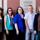 Seven people in a line, for posed picture, outdoors.