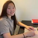 A female student sits at a desk with a laptop 