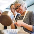 Woman in kitchen holding a sauce pan