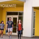 Four students in front of main entrance of new residence hall