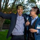 Two male students, one with arms extended in celebration