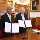 Chancellor May and French official hold up signed doruments in ornate room.
