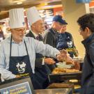 Campus leaders in tall, white chef's hats, serving breakfast.