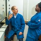 Man and woman in blue lab coats, in a chemistry lab.