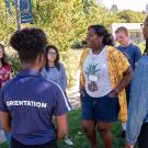 An orientation leader stands with a group of incoming students outdoors.