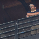 Tim Ornelas high above in media box, next to video camera