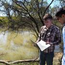 Male scientists with computer by water