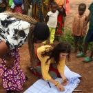 Woman kneels surrounded by children