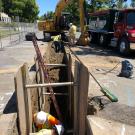 Workers in and around trench in road, for pipeline project.