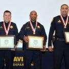 Four police officers in uniform, wearing medals and holding certificates; posing with police chief.