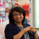 Renetta Garrison Tull, hands clasped, at meeting, smiling.