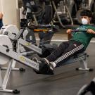 Man wearing face covering uses rowing machine at the ARC.