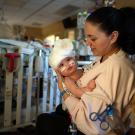 Woman holds baby in hospital.