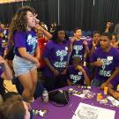 standing female student performs among large group around her