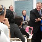 Classroom setting showing students seated and man hugging woman in the front