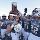 Aggie football players hold up Big Sky trophy.