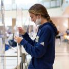 Woman at saliva-sample station, holding collection tube.