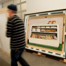 Museum workers remove crate from top of crate holding a Wayne Thiebaud painting.