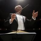 Jeffrey Thomas conducting a performance at night in a hall