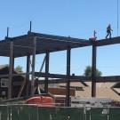 Construction worker walks along steel beam.