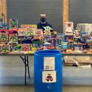 Three man standing behind tables full of toys.