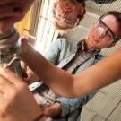 Students in winemaking class extracting processed grapes from a tube, photo taken from below