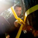 Student ties yellow ribbon around tree.