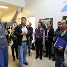 Man points to large wall map as he speaks to group of people in hallway