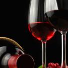 Bottle of wine on its side with a glass of red wine, grapes in the background