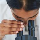 Closeup of woman looking in eye piece of scientific equipment