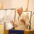 Man in front of paintings, at podium