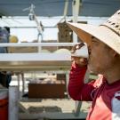 Man in straw hat sipping from cup net to trailer with cantaloupes