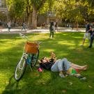 Two students sitting outside on a lawn on a sunny day