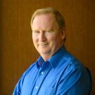 Michael Lairmore photographed in front of a brown wall