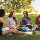 Three students and a staff member smile on the grass at UC Davis. 