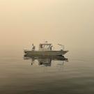 Researcher Brandon Berry from the UC Davis Tahoe Environmental Research Center collects data from a research vessel on the water at Lake Tahoe amid smoke-filled skies. 