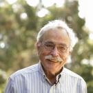 Profile shot of Peter Moyle, smiling in dappled sunlight and tree grove