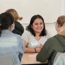 Students smile while sitting around a desk during a UC Davis Teaching Assistant Conference at the Teaching Learning Complex on September 19, 2022.