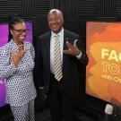 Two smiling presenters in studio beside orange 'Face to Face' set screen