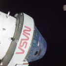 A spacecraft with the text "VSN" and "NASA" against a dark sky, with the moon in the background.