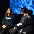 Three students and a woman seated with a screen behind them