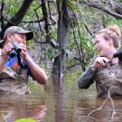Two people are chest deep in flood waters in the Amazon rainforest.