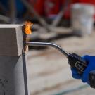 A close-up of a wood block and earth block and a blowtorch