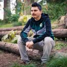 Man sits on log in UC Davis Arboretum's redwood forest