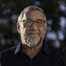 A headshot of Clifford Saron wearing glasses and a dark shirt