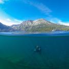 Diver Katie Senft seen underwater Lake Tahoe while mountain and sky are above