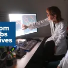 Photo of two scientists looking at a screen with logo superimposed: From Labs to Lives