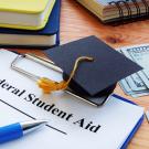 grad cap and student aid application and cash on desk for illustration