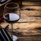 Close up view of a red wineglass shot on rustic wooden table. A wine bottle is laying beside the wineglass. Selective focus on the wineglass. A corkscrew, grapes and a wine bottle box complete the composition. (Getty)