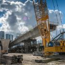 Freeway viaduct construction including a crane and tower blocks in the background. 